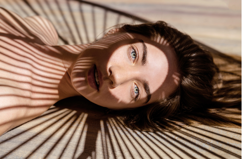 Portrait of beautiful woman with shadows of palm leaf on her face  Concept of sunbathing, vacation 