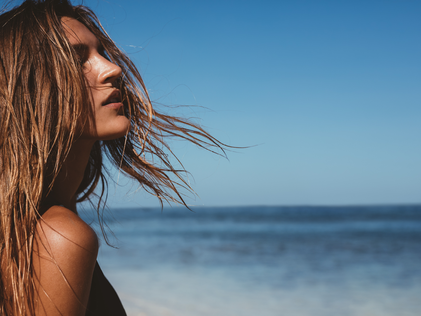 Close up portrait of beautiful young woman on the beach. Young caucasian female model on the sea shore.