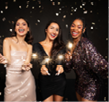 Three happy beautiful young ladies in nice dresses with bengal lights posing in confetti over black background, multiracial girlfriends celebrating New Year together, have xmas party