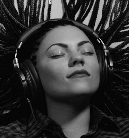 Beautiful young girl with african blue braids is listening to music with headphones and dancing. Woman on bright yellow background. Dyed Hair moves.