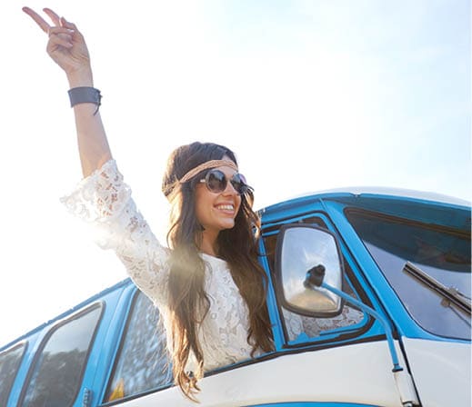 summer holidays, road trip, travel and people concept - smiling young hippie woman showing peace gesture in minivan car