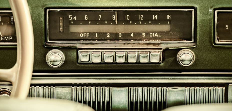 Retro styled image of an old car radio inside a green classic car