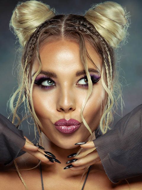 Beauty Girl with pout Full Lips Kiss. Beauty Model Face with Perfect Make up and Black Nails Manicure. Stylish Blond Woman with Two Space Hair Buns Hairstyle over Dark background